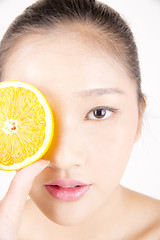 Image showing Beautiful young Asian girl holding orange slice over face