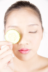 Image showing Beautiful young Asian girl holding cucumber slice over face