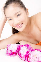 Image showing Beautiful young Asian girl lying down with red peony flowers