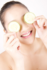 Image showing Beautiful young Asian girl holding cucumber slice over face