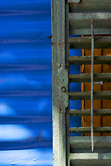 Image showing green iron venetian blind and a blue metal wall