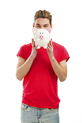 Image showing Handsome young man holding a piggy bank