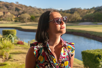 Image showing Young woman in sunglasses enjoying summer breeze at beach. 