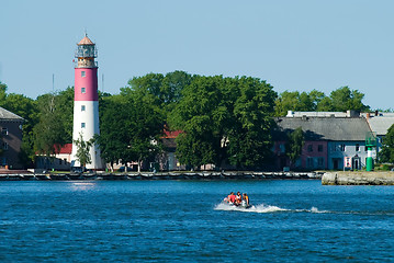 Image showing People in rubber boat and lighthouse is Baltiysk