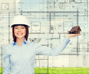 Image showing businesswoman in helmet holding house on palm