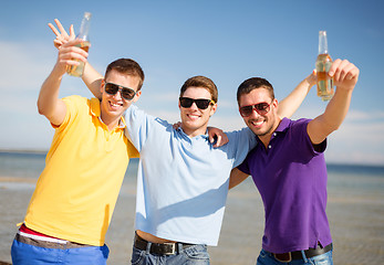 Image showing happy friends with beer bottles on beach