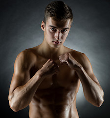 Image showing young man on fighting stand over black background