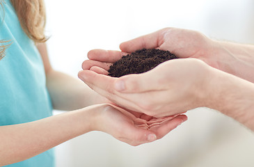 Image showing close up of father and girl hands holding sprout