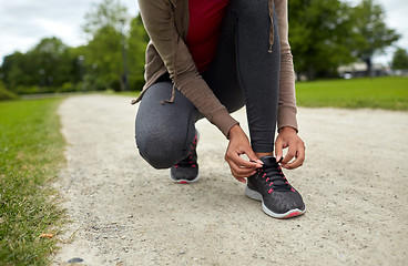 Image showing close up of woman tying shoelaces outdoors