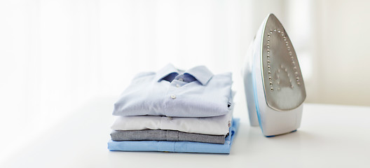 Image showing close up of iron and clothes on table at home