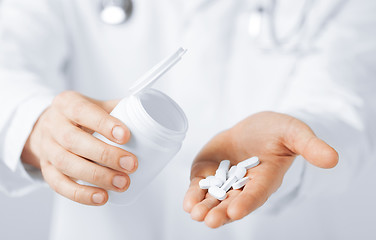 Image showing doctor hands holding white pack and pills