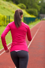 Image showing woman running on track outdoors from back