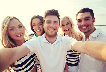 Image showing happy friends on beach and taking selfie