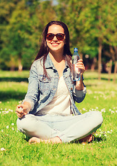 Image showing smiling young girl with bottle of water in park