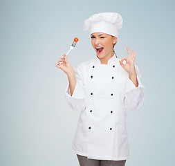 Image showing smiling female chef with fork and tomato