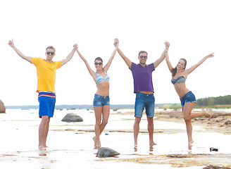 Image showing group of happy friends holding hands on beach