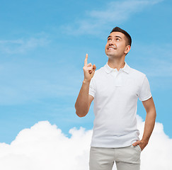 Image showing smiling man pointing finger up over blue sky