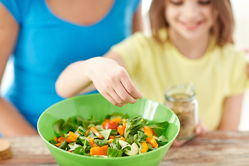 Image showing close up of happy family cooking salad in kitchen