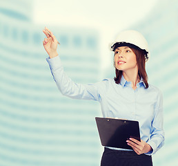 Image showing smiling businesswoman in helmet with clipboard