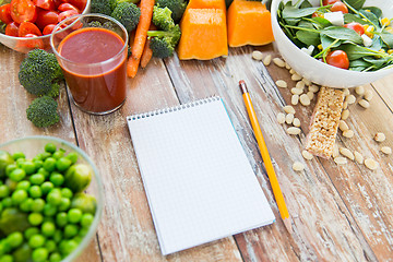 Image showing close up of ripe vegetables and notebook on table