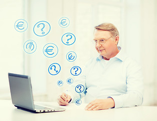 Image showing old man in eyeglasses filling a form at home