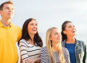 Image showing group of happy friends looking up on beach
