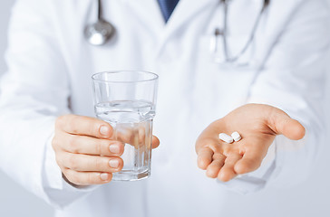 Image showing doctor hands giving white pills and glass of water