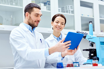 Image showing scientists with tablet pc and microscope in lab