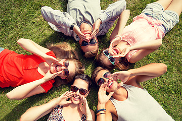 Image showing group of smiling friends lying on grass outdoors