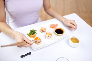 Image showing close up of woman eating sushi at restaurant