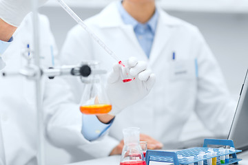 Image showing close up of scientists filling test tube in lab