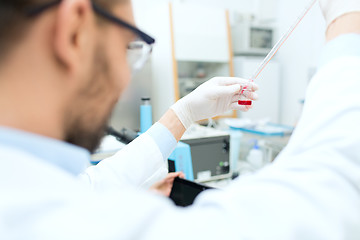 Image showing close up of scientist with tube and pipette in lab