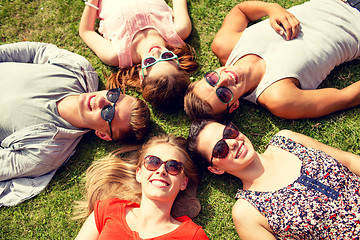 Image showing group of smiling friends lying on grass outdoors