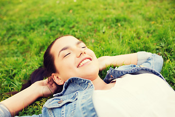 Image showing smiling young girl with closed eyes lying on grass