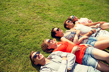 Image showing group of smiling friends lying on grass outdoors