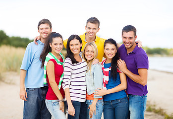 Image showing group of happy friends hugging on beach