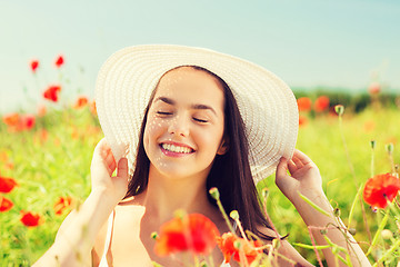 Image showing smiling young woman in straw hat on poppy field