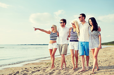 Image showing smiling friends in sunglasses walking on beach