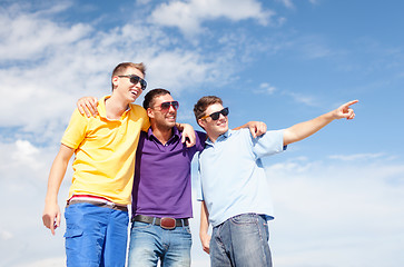 Image showing smiling friends in sunglasses pointing finger