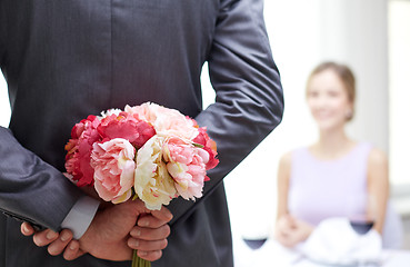 Image showing close up of man hiding flowers behind from woman