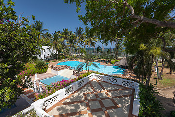 Image showing Swimming pool, palm trees, pink flowers and blue sky