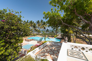 Image showing Swimming pool, palm trees, pink flowers and blue sky