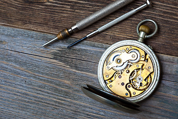 Image showing antique clock with an open mechanism and two screwdrivers