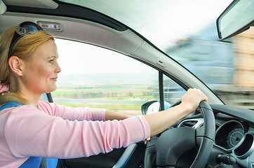 Image showing Attractive adult woman safe carefully driving car suburban road
