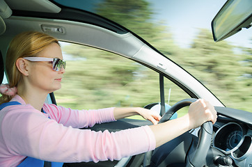 Image showing Pretty woman in sunglasses driving fast car