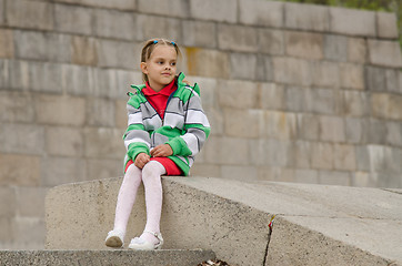 Image showing girl looks into distance while sitting a granite embankment on ramp