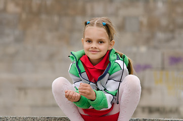 Image showing Six year old girl crouched on the background of a granite wall