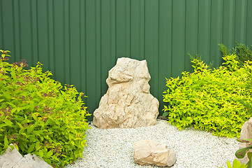 Image showing Fragment of the garden with green bushes and bright stones.