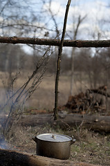 Image showing Cooking in old sooty cauldron on campfire