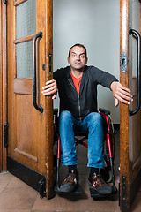 Image showing Man in wheelchair stuck between swing doors